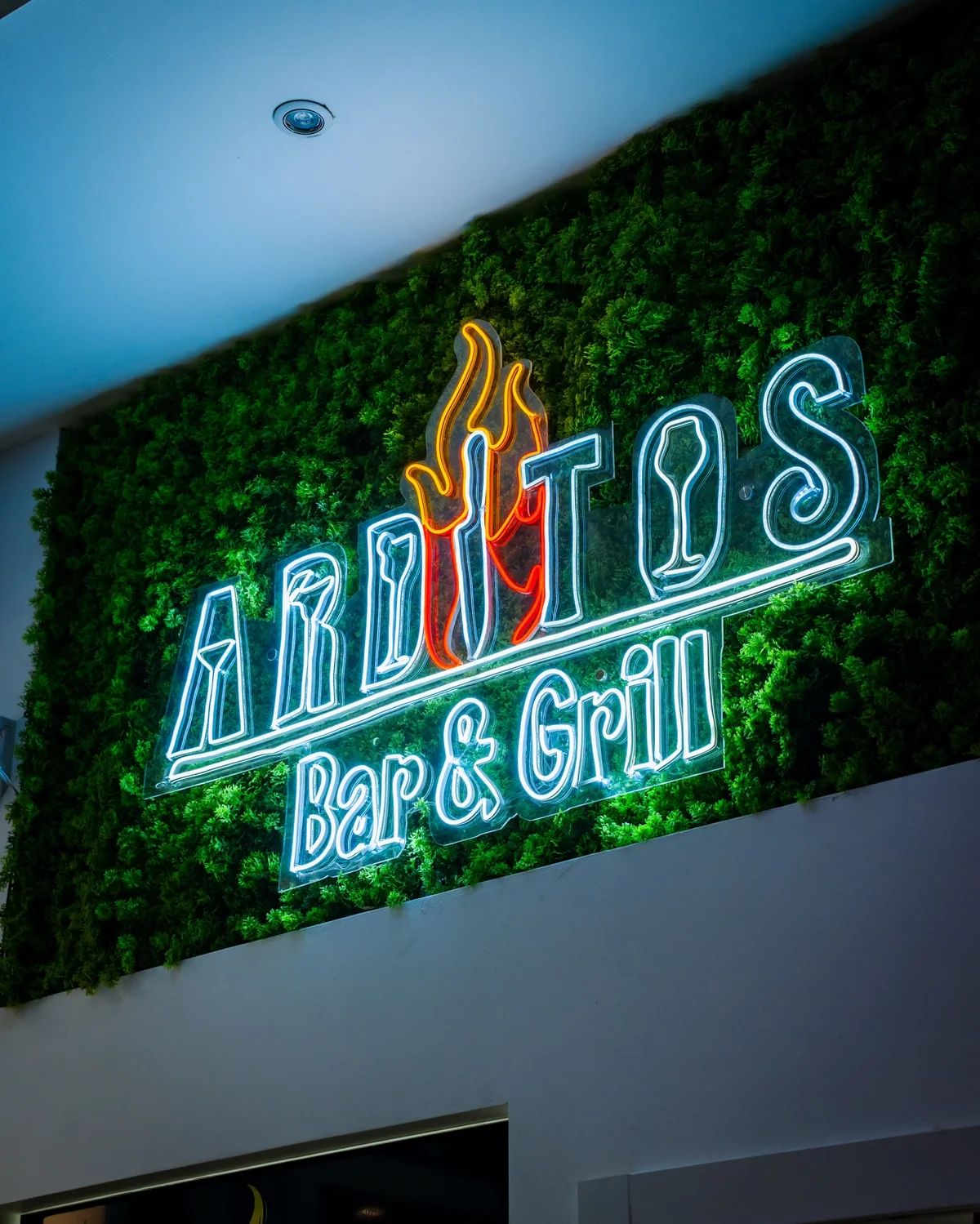 Insegna luminosa Ardito’s Bar & Grill sulla parete verde del locale